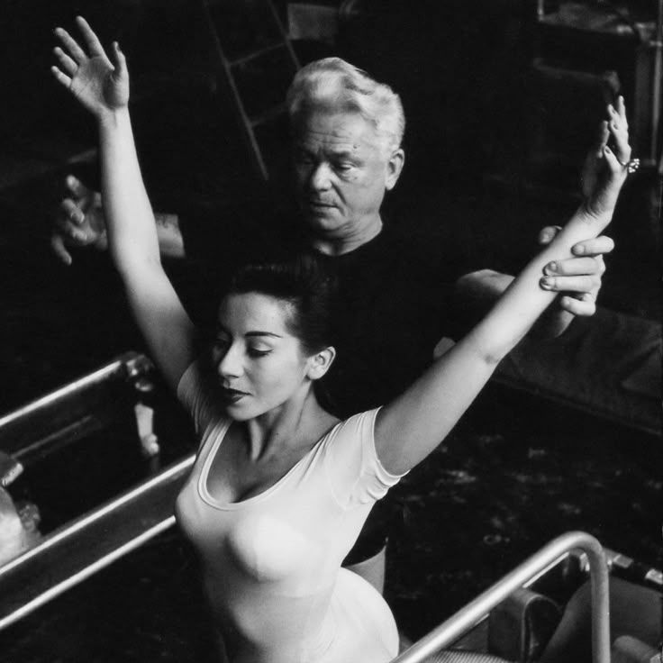 Joseph Pilates corregge un'allieva — lo sguardo abbassato, le braccia in apertura, la concentrazione totale. I sei principi non si spiegano: si sentono.