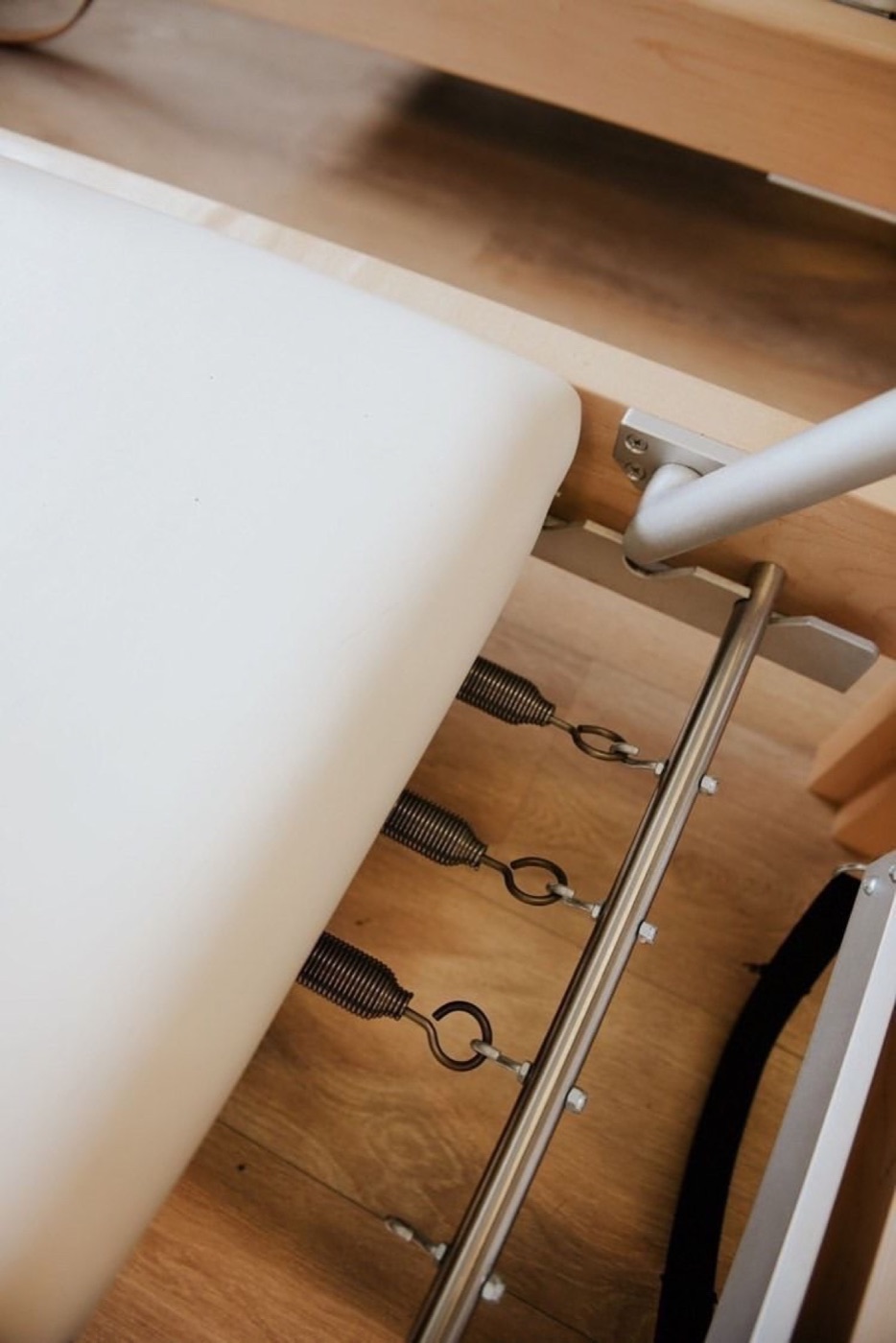 Detail of Reformer springs and frame at Spazio Pilates Grosseto, classical Gratz apparatus on wooden floor